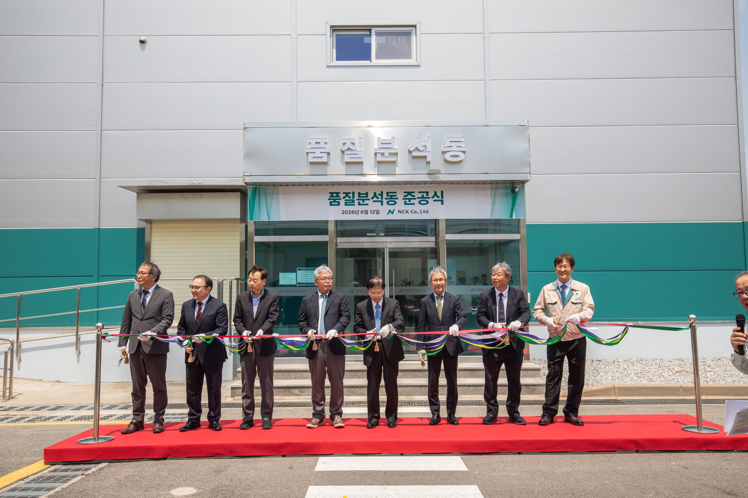 새로 준공한 건물 출입구 앞에서 진행되는 준공식 테이프 커팅